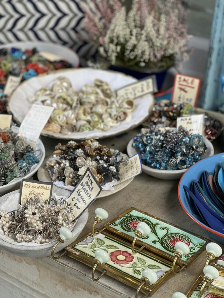 Colorful market stall with diverse handmade jewelry and accessories on display in bowls.