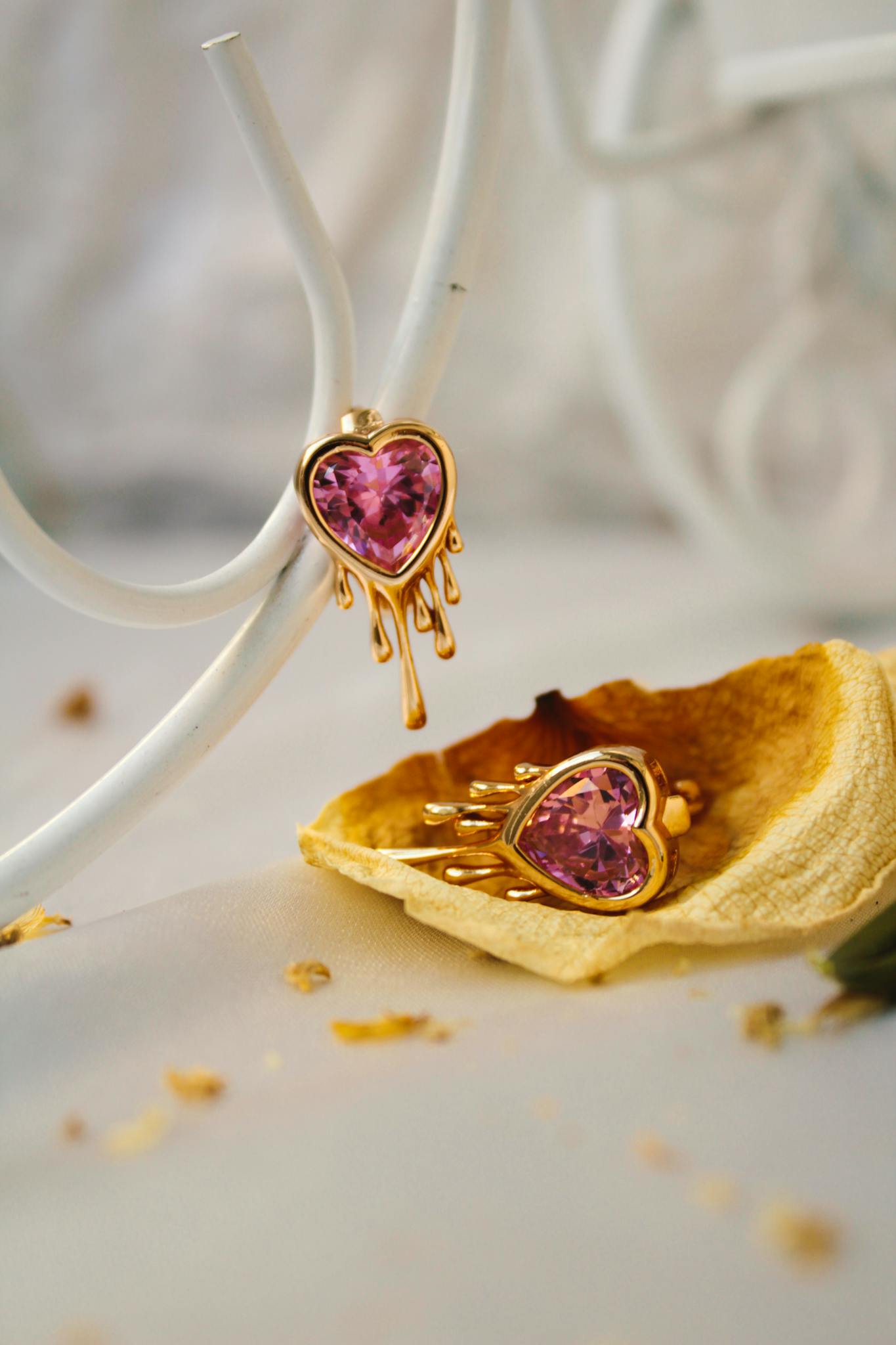 Stylish golden earrings with pink heart stones elegantly displayed indoors.